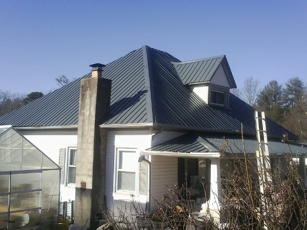 Dark blue standing seam metal roof on a white farmhouse with dormer — Slate & Tile Roof Repair by Roofing Brothers in Worcester