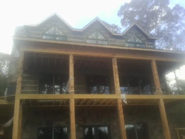 Dormers and porch framing on a large log home under construction — Roof Coating work by our crew in Worcester