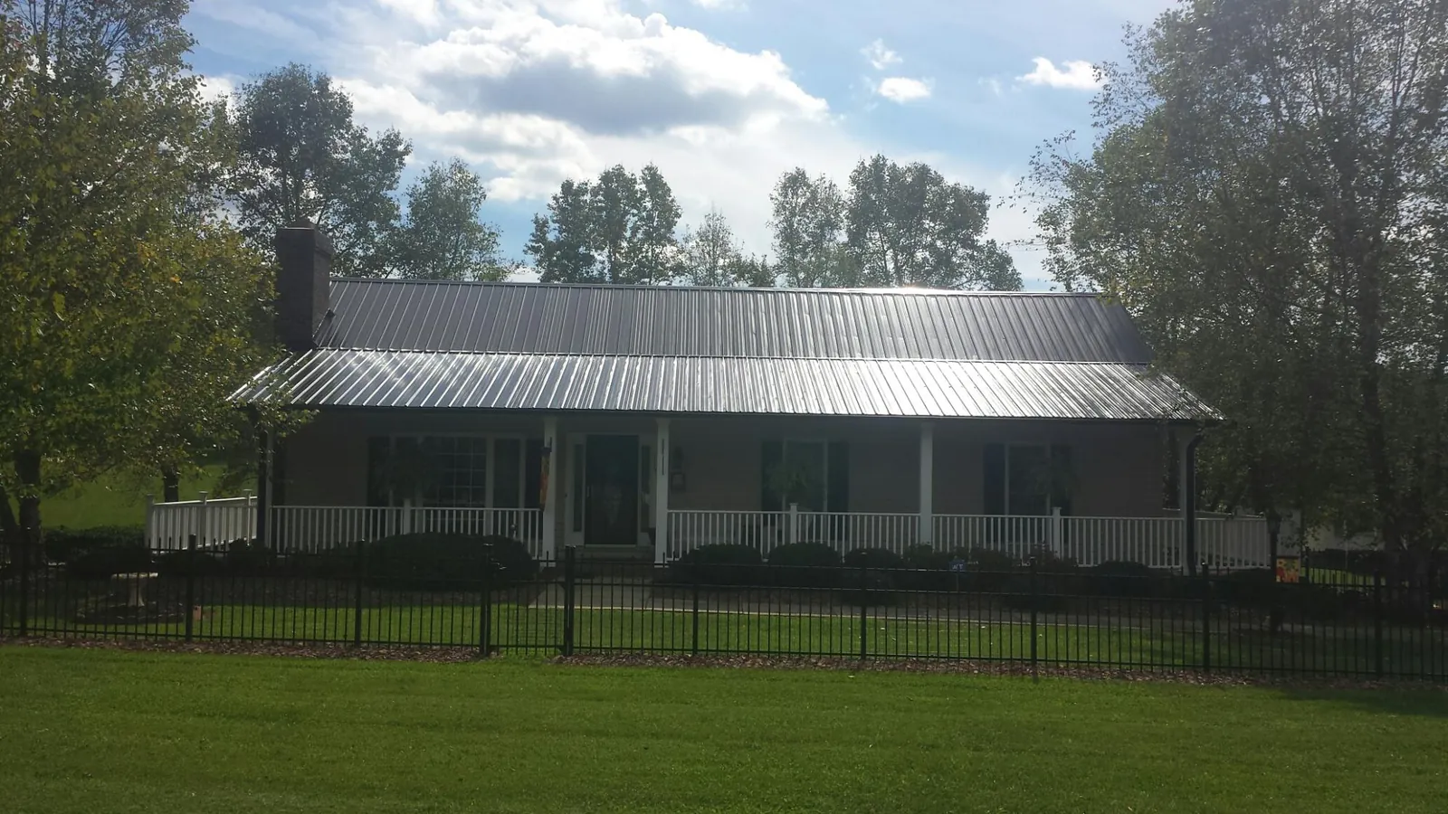Gray metal roof on a brick ranch with a full width front porch — Gutter Guard Installation work by our crew in Worcester