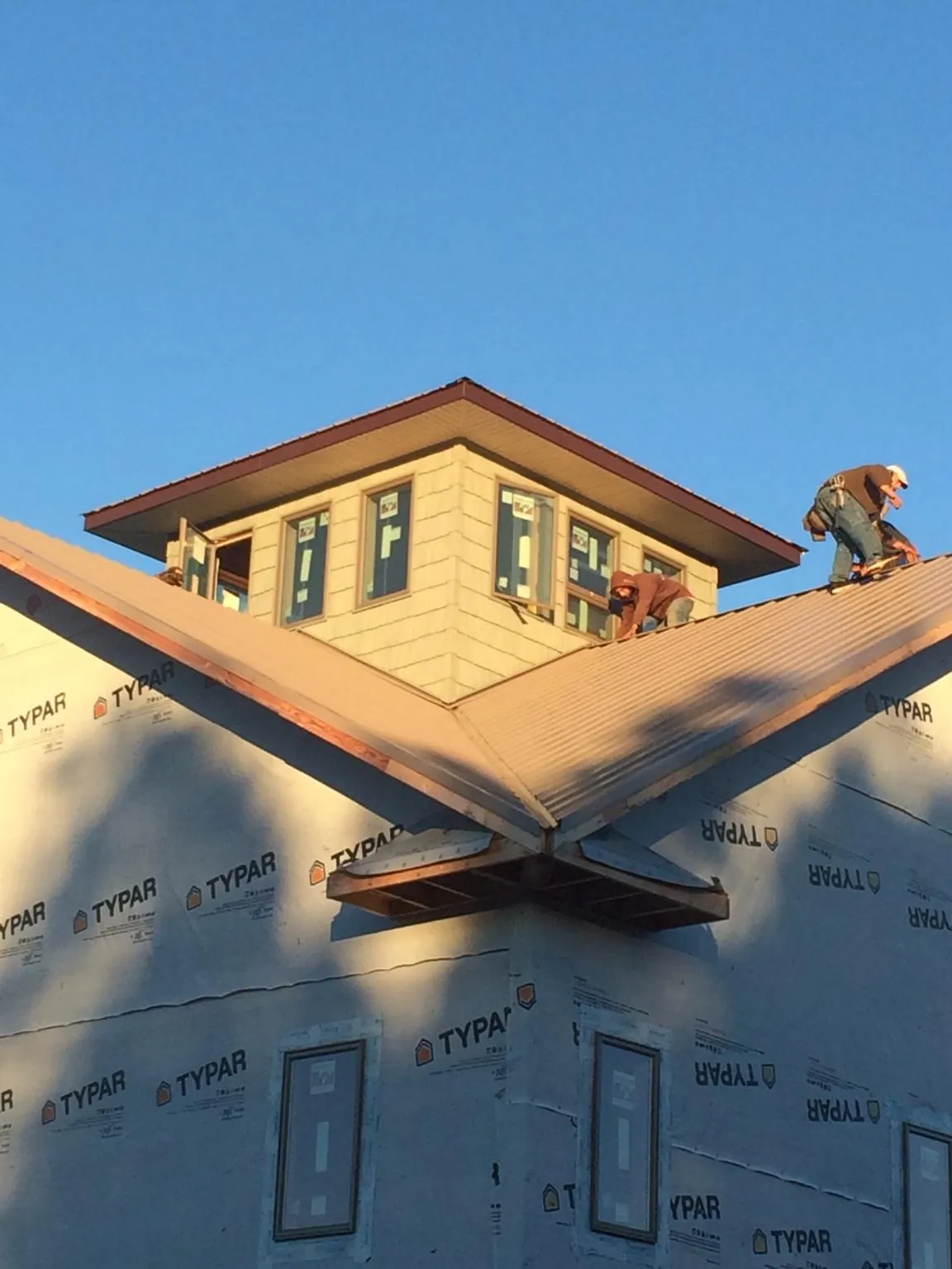 Roofers working around a rooftop cupola on a new metal roof at sunset — Roof Waterproofing in Worcester by Roofing Brothers
